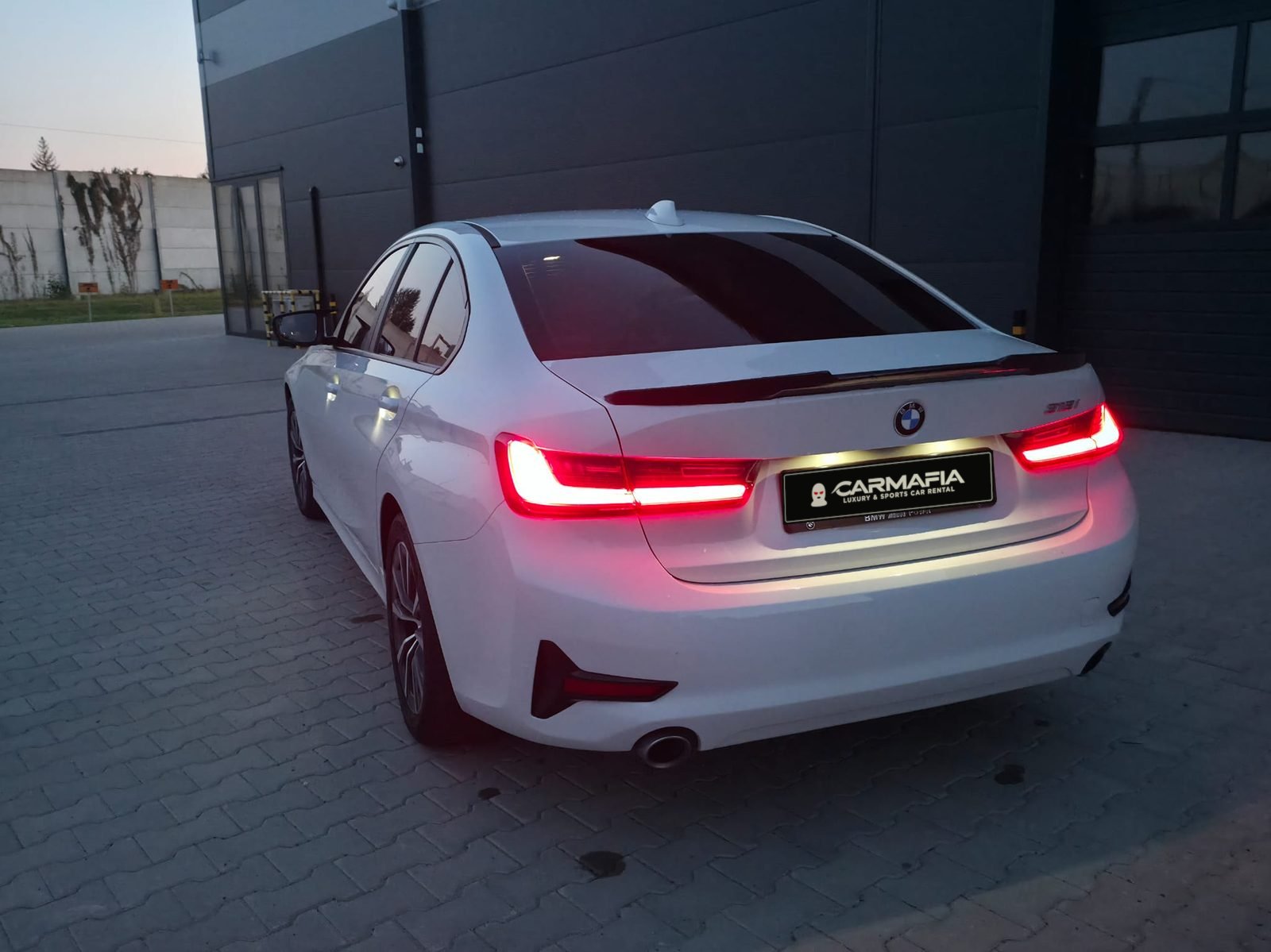 Tył białego BMW 318i G20 2020 z włączonymi światłami i tablicą CarMafia.fun