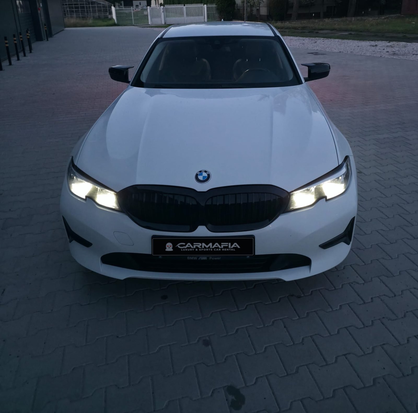 Białe BMW 318i G20 2020 z góry, od przodu, z włączonymi reflektorami