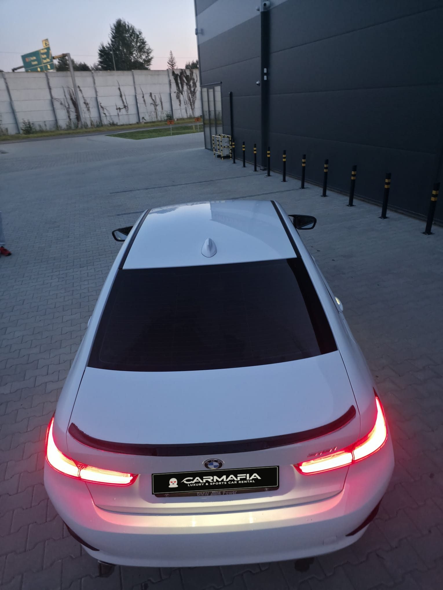Białe BMW 318i G20 2020 z góry, od tyłu, z włączonymi światłami